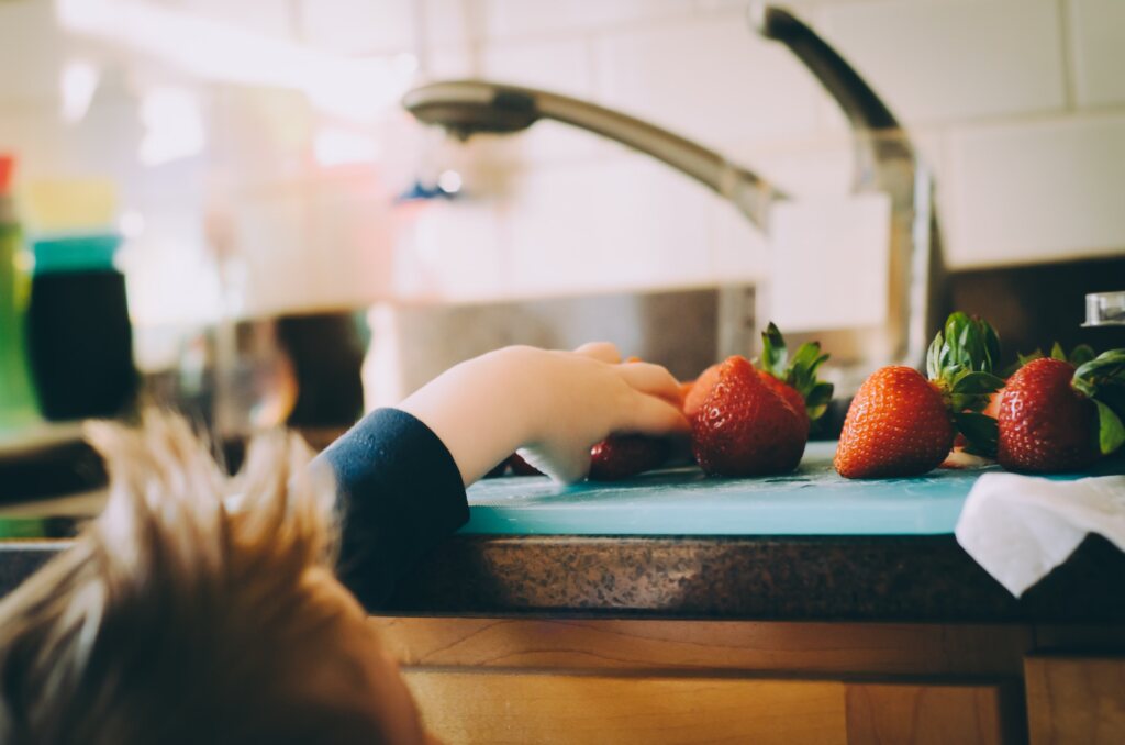 child grabbing strawberries off the counter