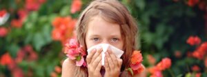 Mold allergies or seasonal allergies? Girl outside sneezing, blowing nose