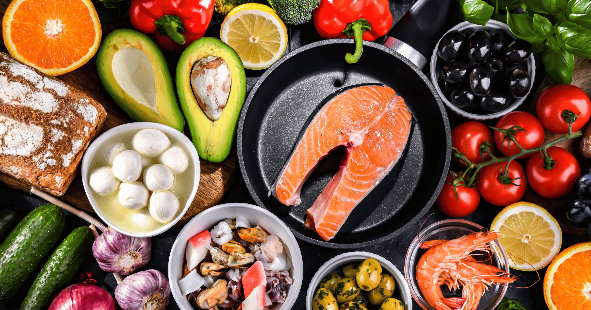 Mediterranean diet foods for heart health, including salmon, avocado, olive oil, fresh vegetables, citrus fruits, whole grain bread, and seafood for heart health.