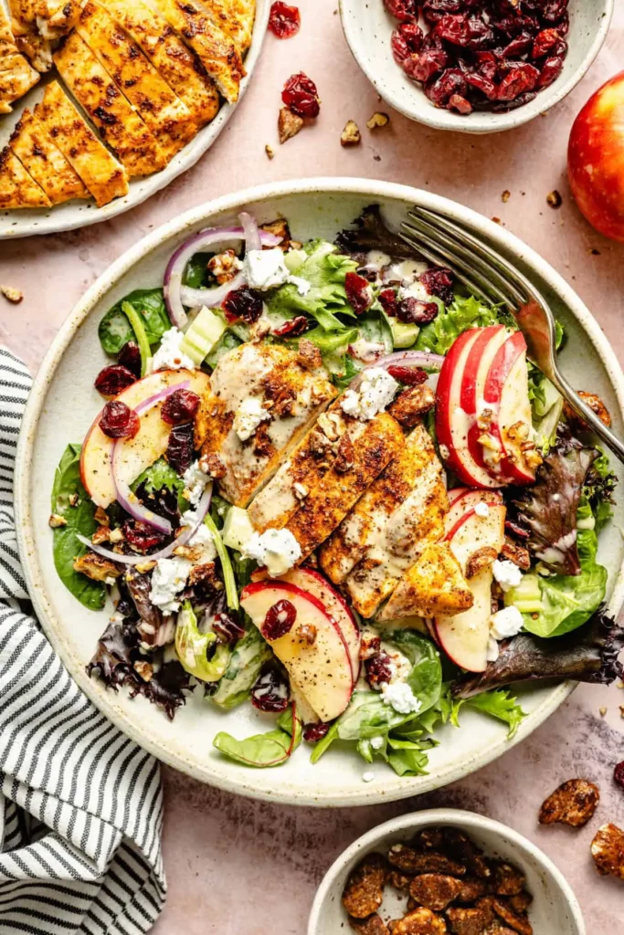 Fall apple salad with grilled chicken, fresh apples, mixed greens, dried cranberries, pecans, red onion, goat cheese, and hot honey dressing.