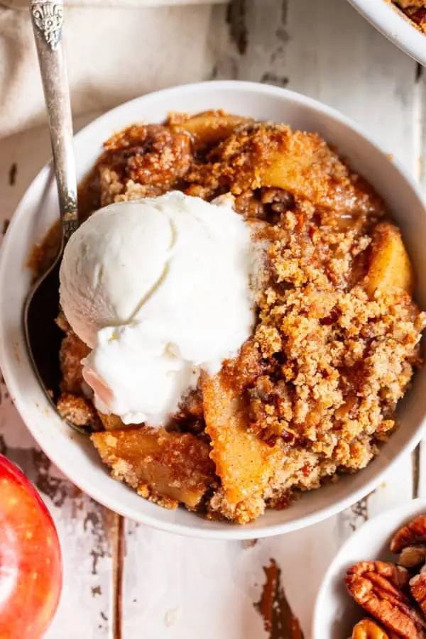 Warm maple pecan apple crisp topped with vanilla ice cream for a gluten-free, dairy-free-friendly fall dessert.